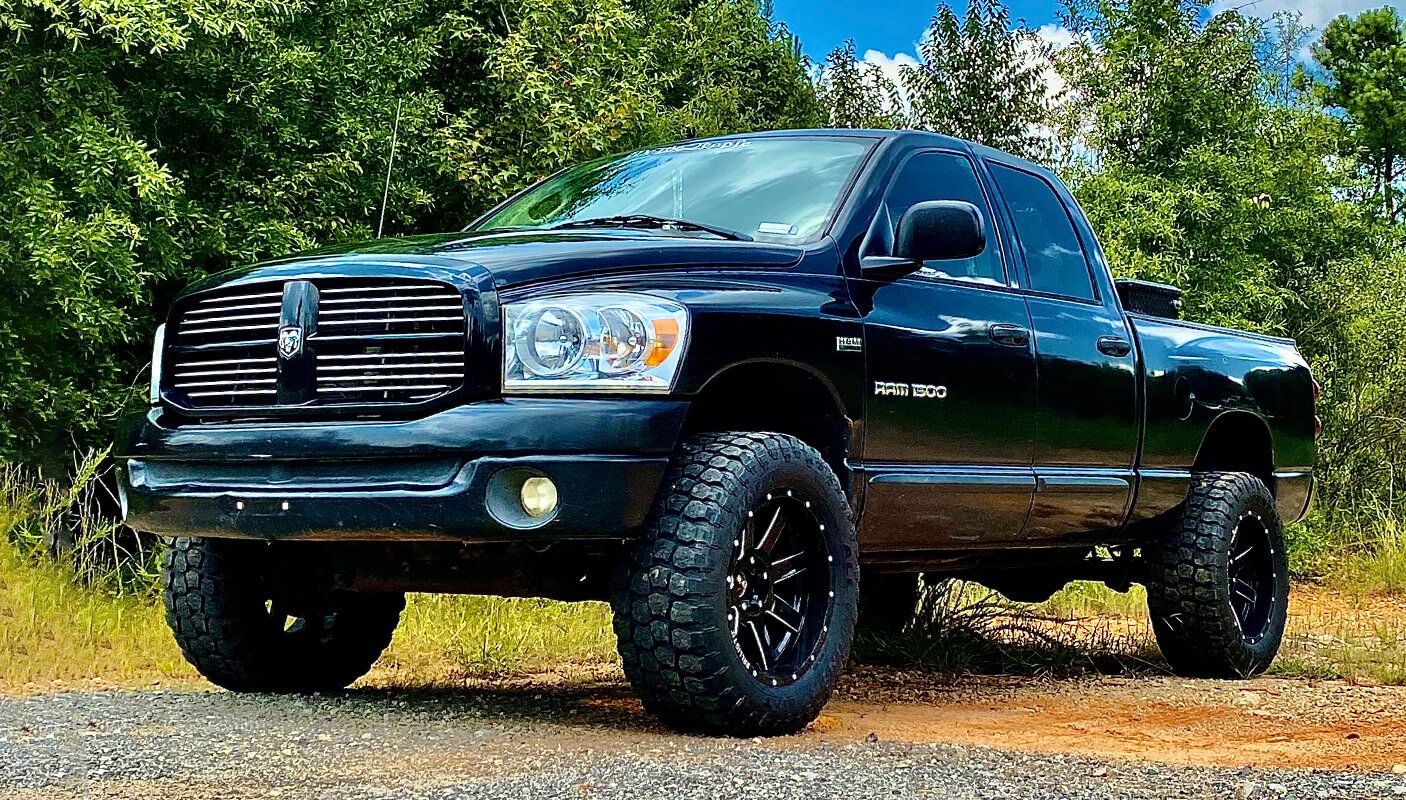 Black Dodge Ram 1500 next to woods